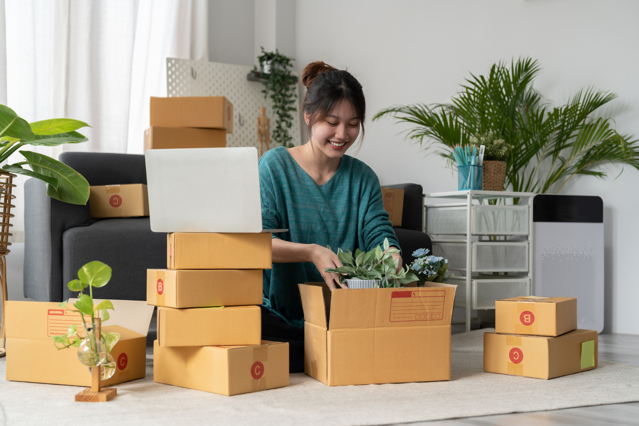 Happy young businessman owner packing plant to cardboard box